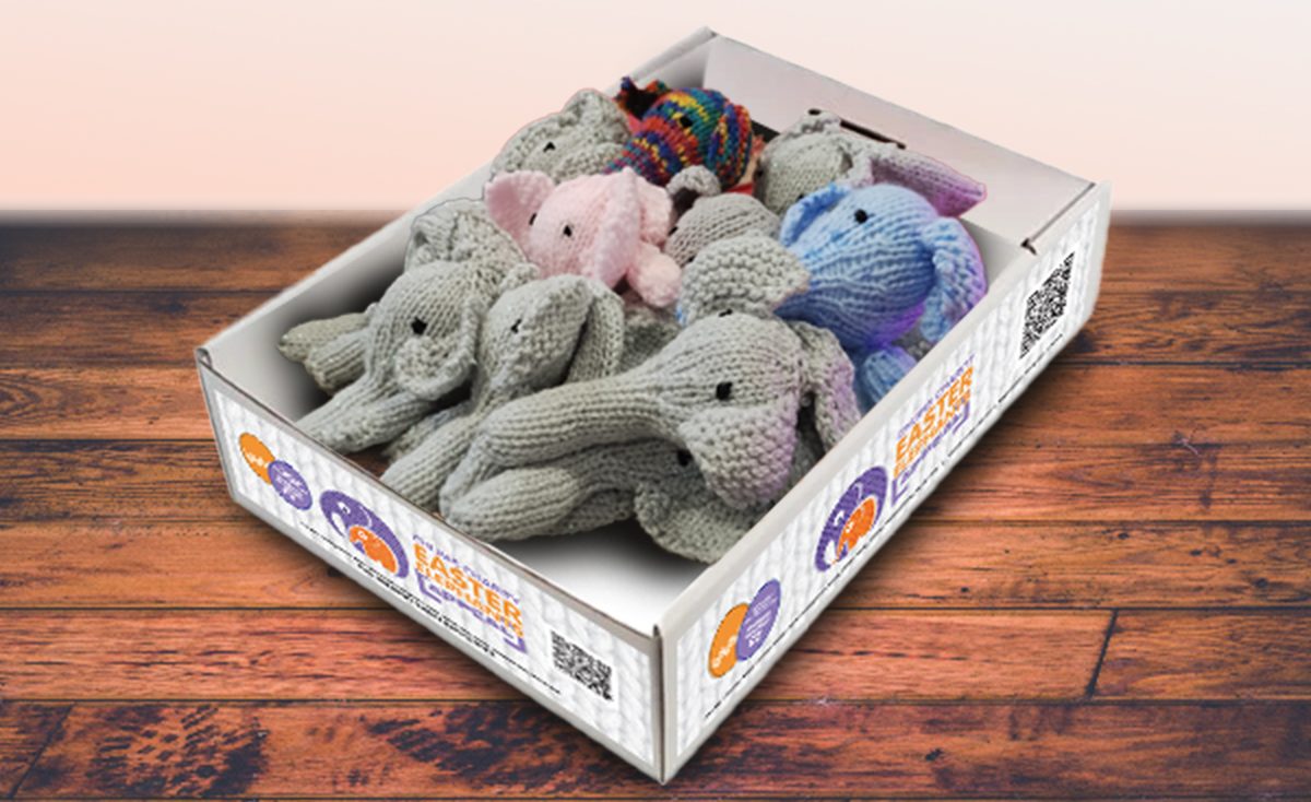 Knitted elephants laid out in a branded display box with the CHUMS logo on